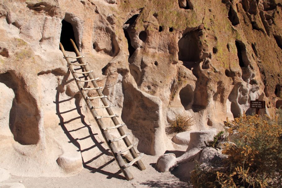 A wooden ladder leads up to a small cave entrance in a weathered, rocky cliff face with several holes and alcoves, offering shelter from the elements and temp fluctuations. A wooden ladder leads up to a small cave entrance in a weathered, rocky cliff face with several holes and alcoves, offering shelter from the elements and temp fluctuations.