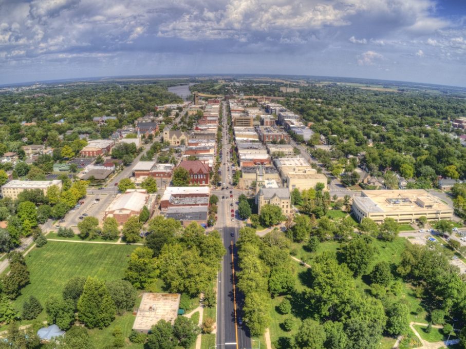 Aerial view of Lawrence, Kansas, with tree-lined streets, low-rise buildings, and green spaces under a partly cloudy sky—perfect for a travel guide.